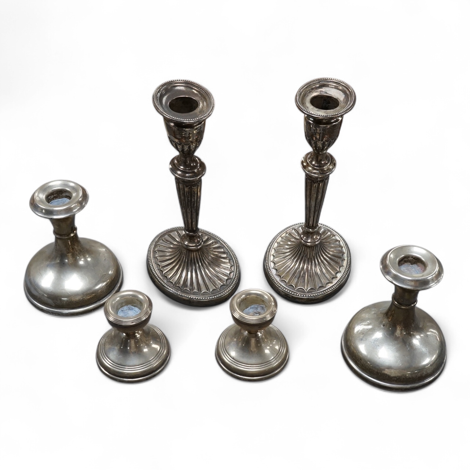 A pair of late Victorian silver mounted oval candlesticks, with bats wing decoration, Sheffield, 1896, 18.2cm, together with two later pairs of silver mounted dwarf candlesticks, all weighted. Condition - poor to fair